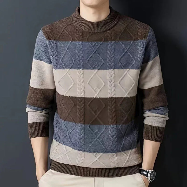 Man wearing a striped cable knit sweater in brown, blue, and beige with long sleeves, against a dark background