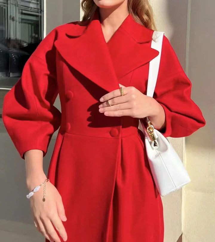 Woman wearing a stylish red double-breasted coat with balloon sleeves and holding a white handbag