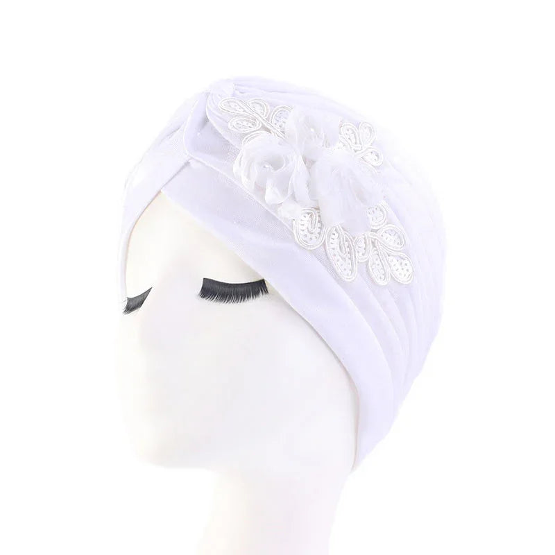 White turban headwrap with floral lace and fabric flower decoration on mannequin head