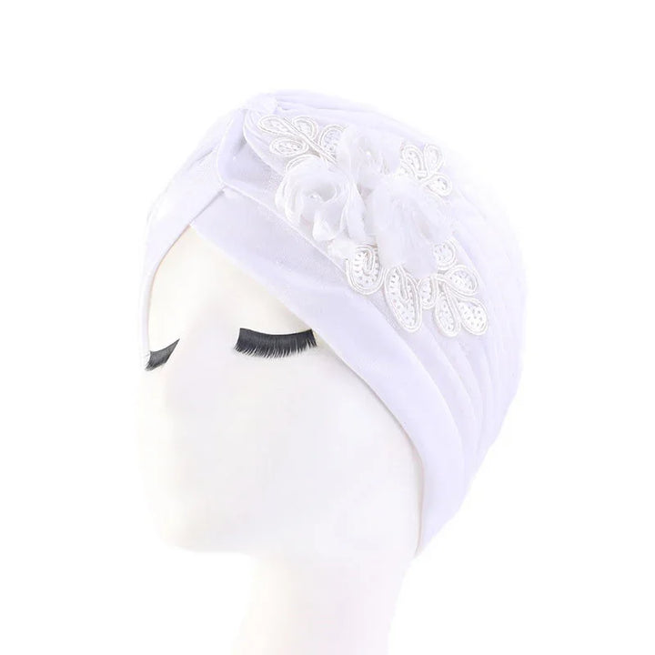 White turban headwrap with floral lace and fabric flower decoration on mannequin head