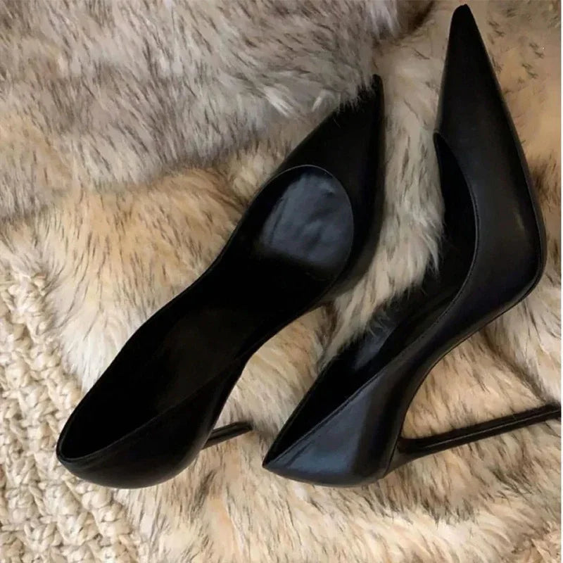 Pair of black pointed-toe high heel shoes on beige faux fur surface