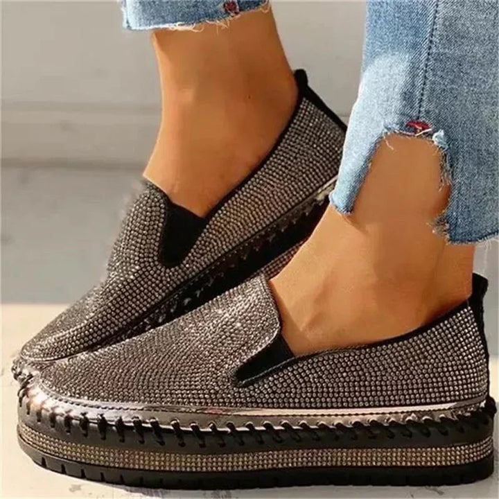 Womens platform slip-on shoes with black and silver rhinestones worn with frayed blue jeans
