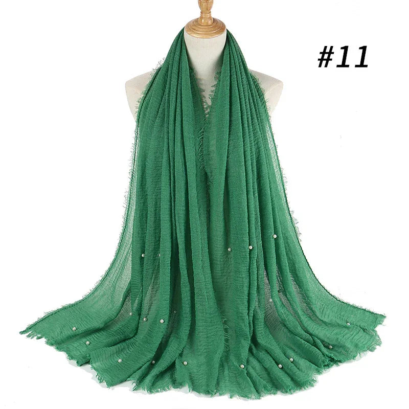 Green lightweight scarf with frayed edges and small pearl embellishments displayed on a dress form