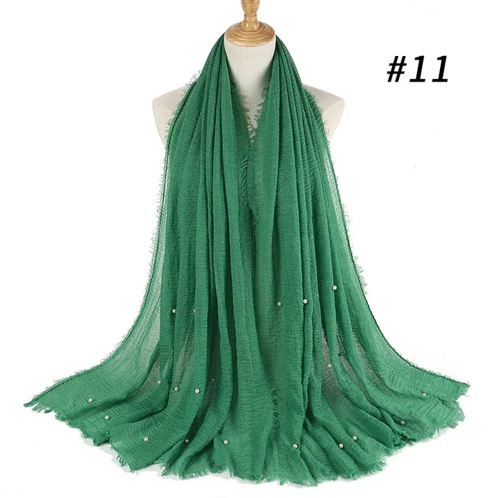 Green lightweight scarf with frayed edges and small pearl embellishments displayed on a dress form