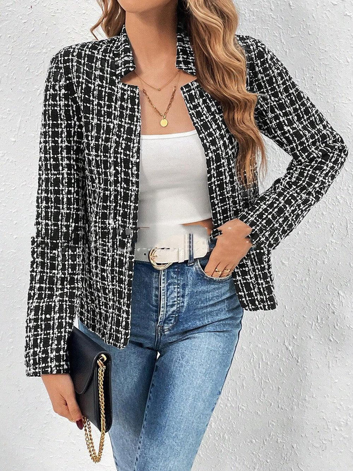 Woman wearing black and white checkered tweed blazer, white crop top, blue high-waist jeans, and holding black clutch