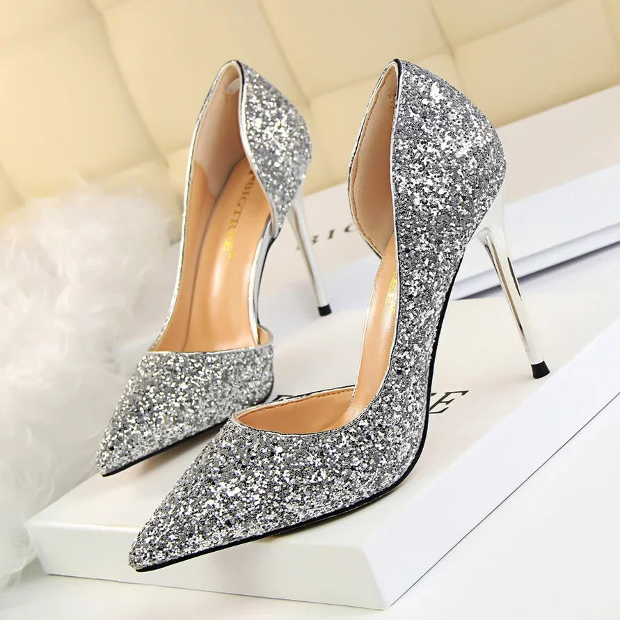 Pair of silver glitter high heel pumps with pointed toes on a white box