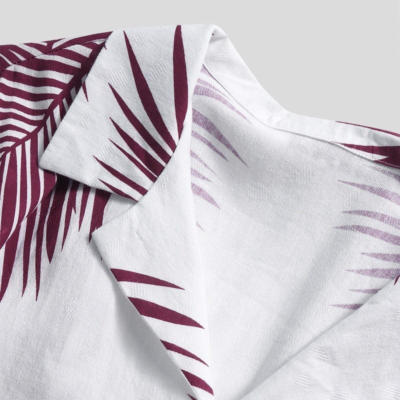 Close-up of a white fabric with maroon tropical leaf print and a folded collar detail