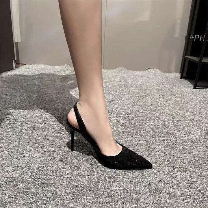 Elegant black slingback high heel shoe with pointed toe worn on foot against gray carpet