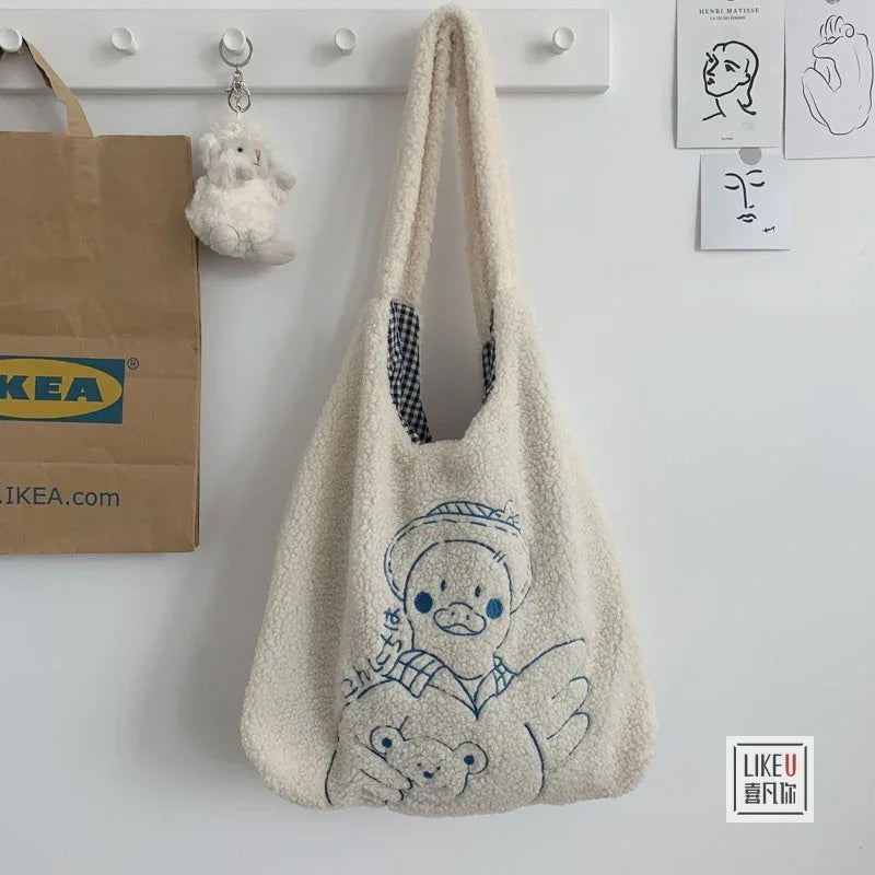 Cozy white sherpa tote bag with cartoon duck and bear design hanging on wall hook