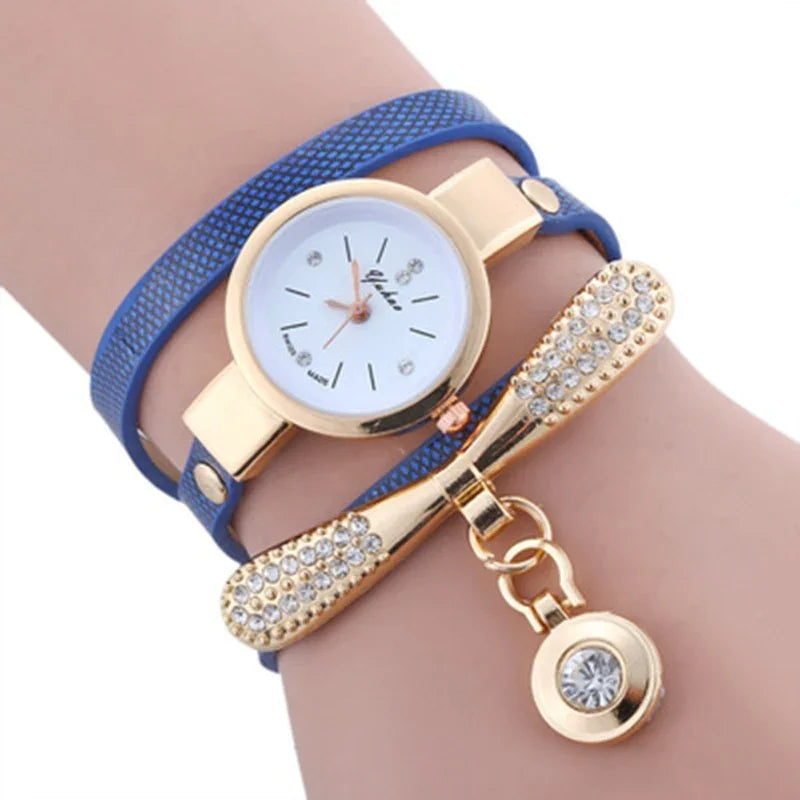 Women's blue leather wrap watch with gold bow and crystal charm on wrist