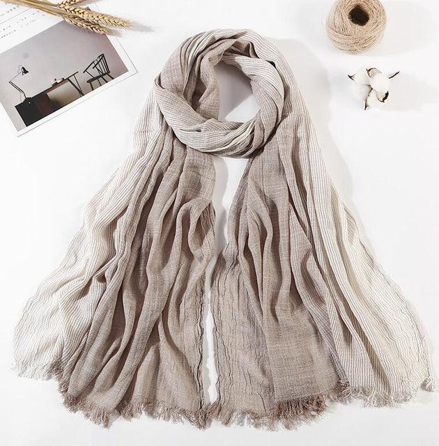 Soft beige and cream striped scarf laid flat with textured fabric and fringed edges, styled with cotton and twine