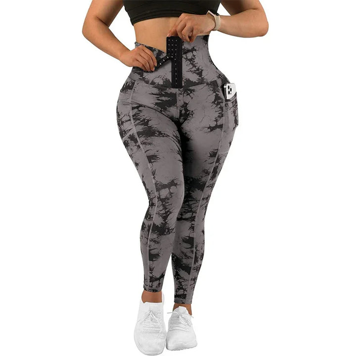 Woman wearing high-waisted gray and black tie-dye workout leggings with side phone pocket and white sneakers