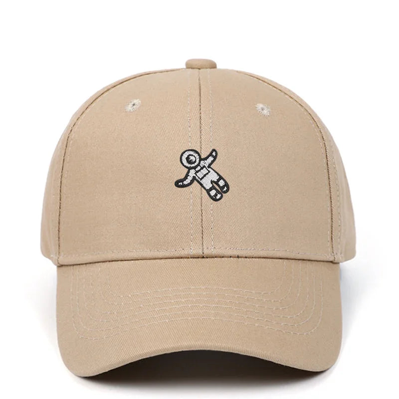 Beige baseball cap with small embroidered black and white astronaut figure on front