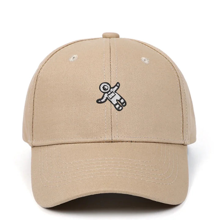 Beige baseball cap with small embroidered black and white astronaut figure on front