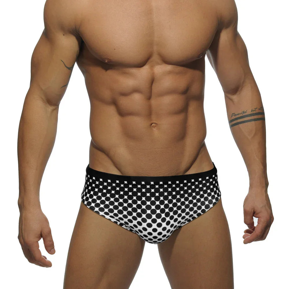 Muscular man wearing black and white polka dot briefs with tattoos on arms