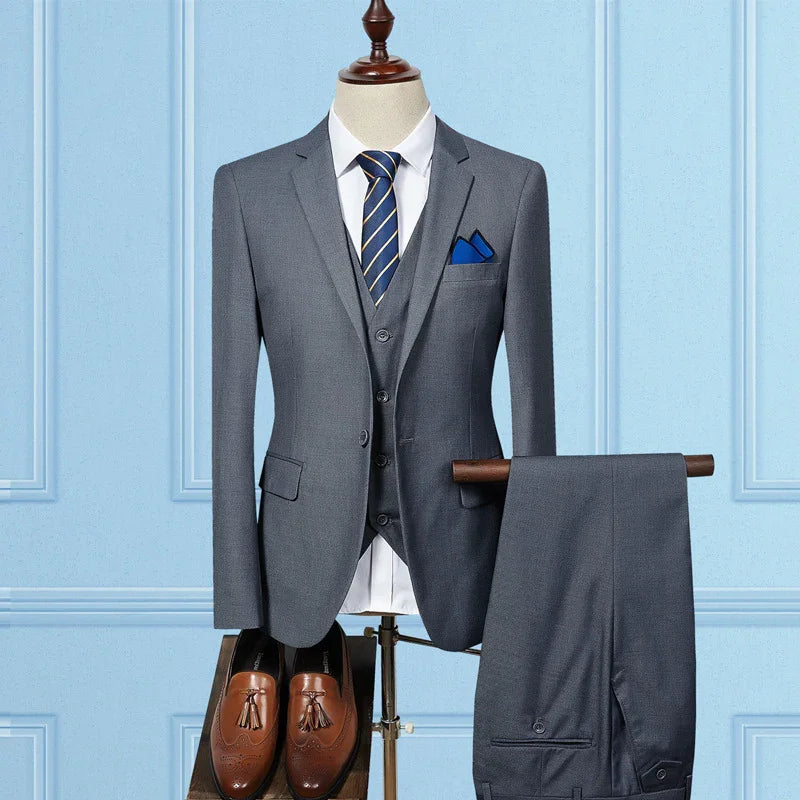 Men's gray three-piece suit with navy striped tie, blue pocket square, and brown tassel dress shoes