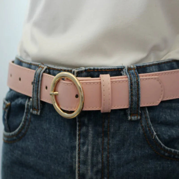 Close-up of pink leather belt with gold oval buckle worn with blue denim jeans and white shirt