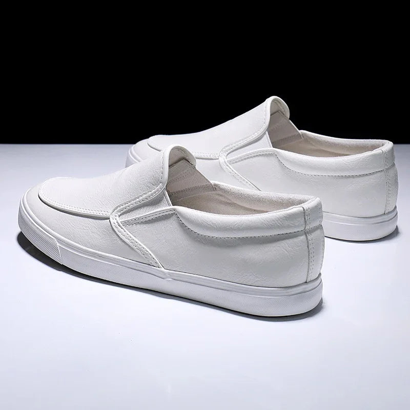 Pair of white slip-on casual shoes with rubber soles on a white surface and black background