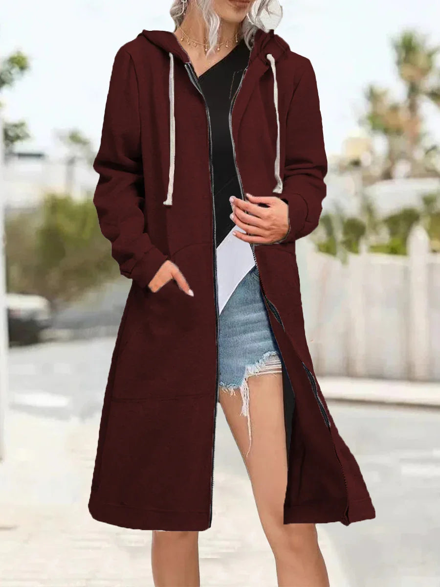 Woman wearing a long burgundy zip-up hoodie with white drawstrings, black top, and ripped denim shorts