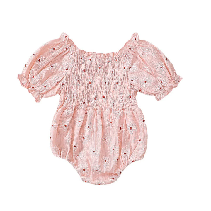 Pink baby romper with puff sleeves and white daisy floral print on white background