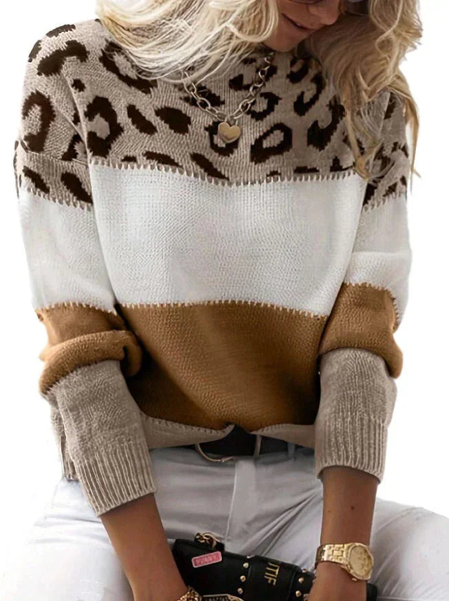 Woman wearing a color-block leopard print sweater with white, brown, and beige tones, paired with white pants and gold accessories