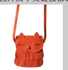 Small red-orange crossbody bag shaped like a sleeping fox with fringe details