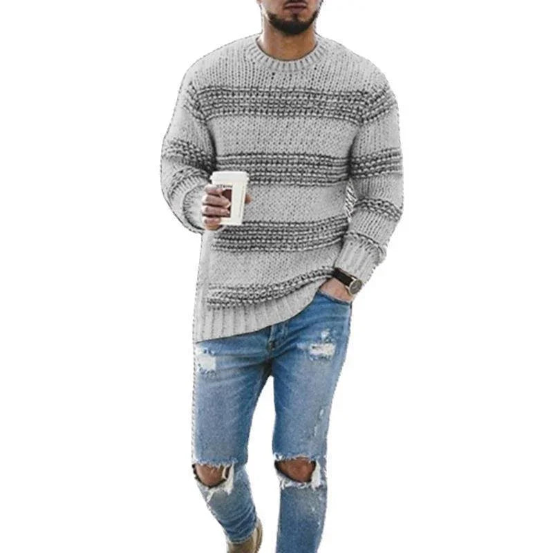 Man wearing gray striped knit sweater and ripped blue jeans holding coffee cup