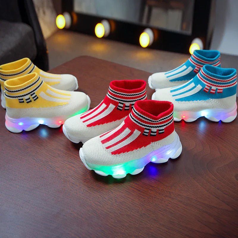 Colorful kids LED light-up sneakers in yellow, red, and blue knit design on wooden surface