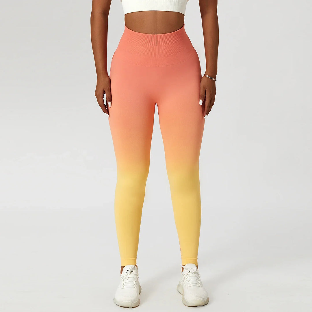 Woman wearing orange to yellow ombre seamless leggings and white crop top on white background