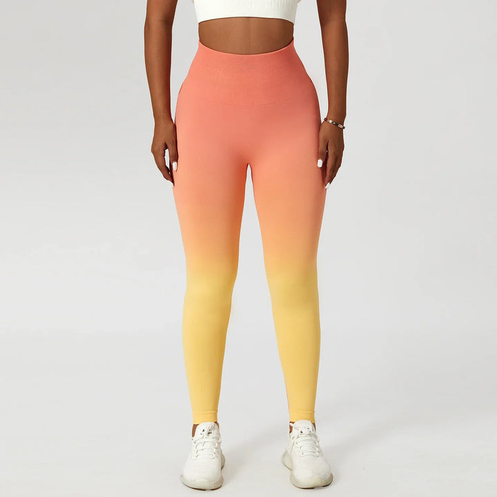 Woman wearing orange to yellow ombre seamless leggings and white crop top on white background