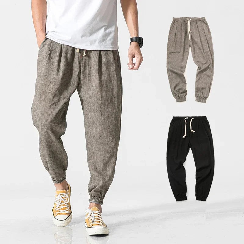 Men's casual drawstring jogger pants in beige and black with elastic cuffs, worn with yellow sneakers