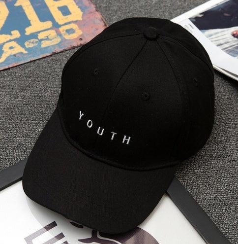 Black baseball cap with white embroidered text 'YOUTH' on a textured gray surface