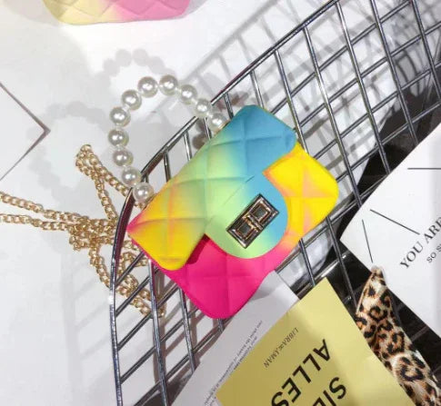 Colorful quilted handbag with gradient rainbow colors and pearl handle on metal rack