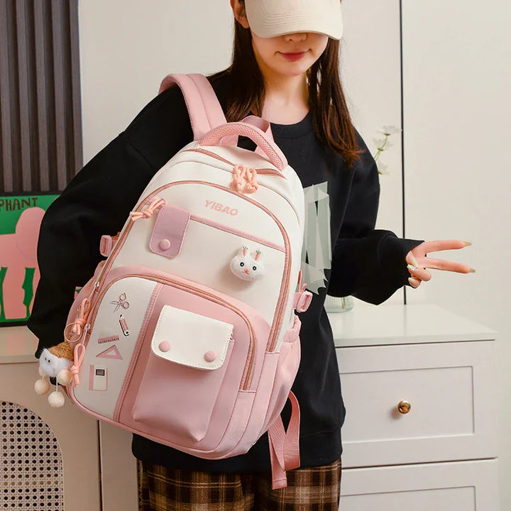Woman wearing pink and white YIBAO backpack with cute bunny keychain and school supplies design