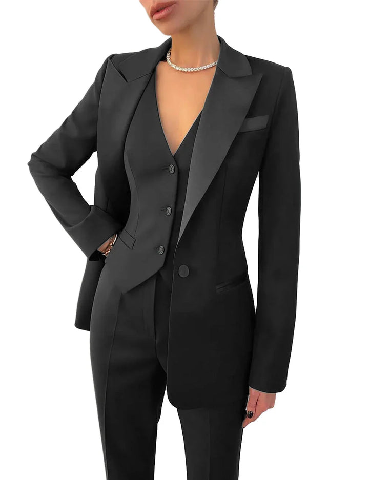 Woman wearing stylish black tailored suit with blazer, vest, trousers, and pearl necklace