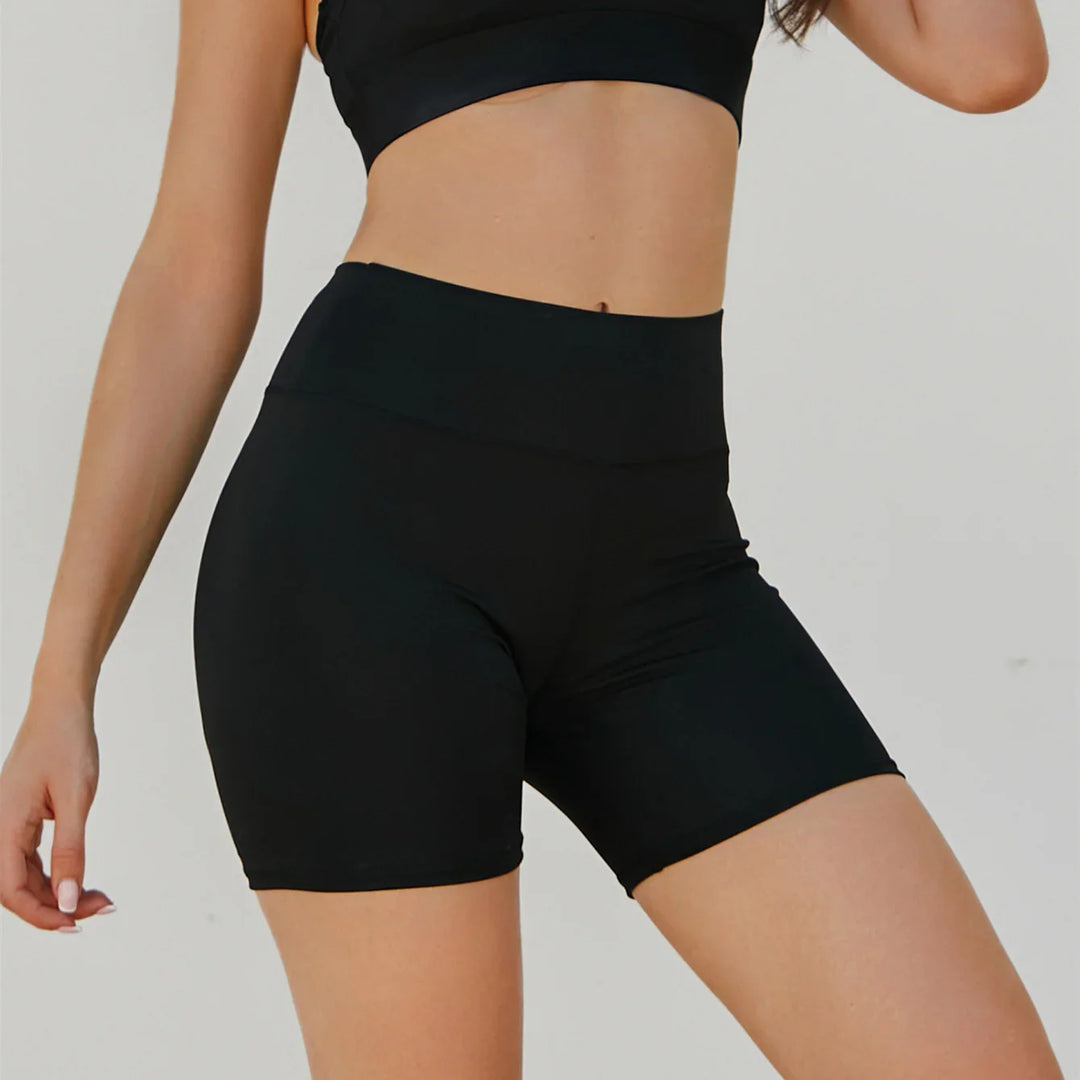 Woman wearing black high-waisted compression biker shorts with a black crop top