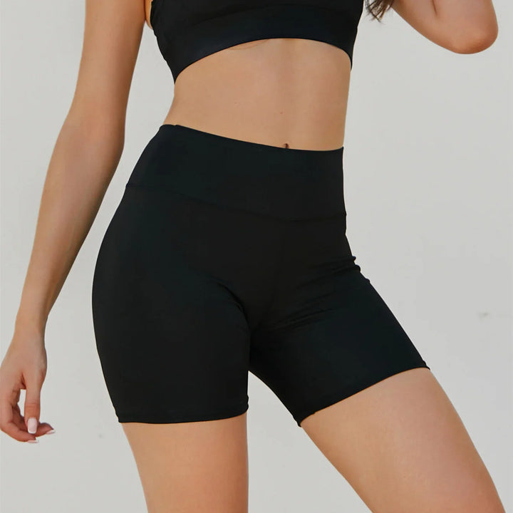 Woman wearing black high-waisted compression biker shorts with a black crop top