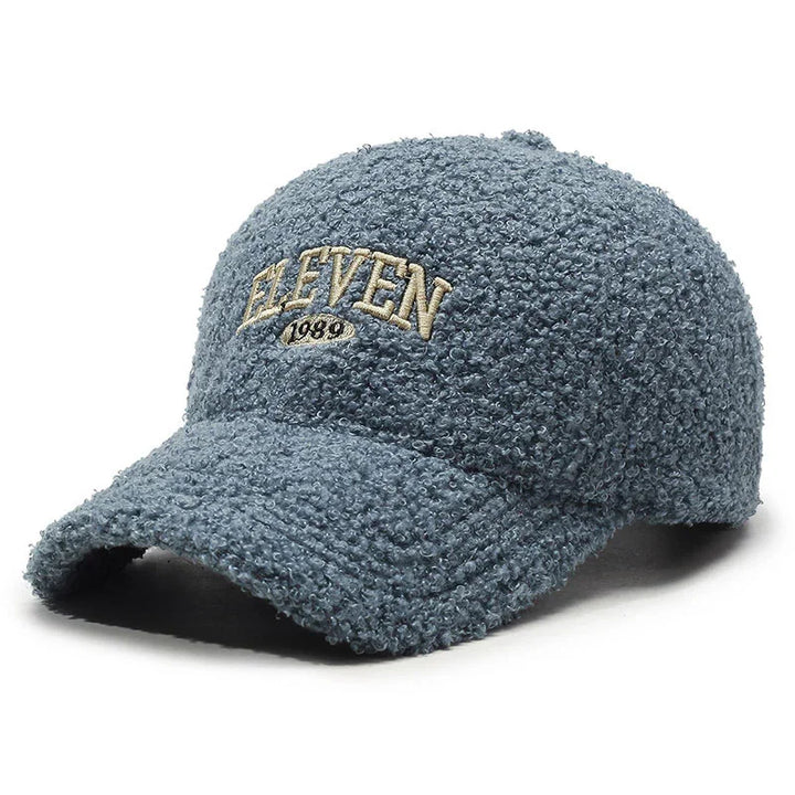 Blue textured baseball cap with beige embroidered text 'ELEVEN 1989' on front