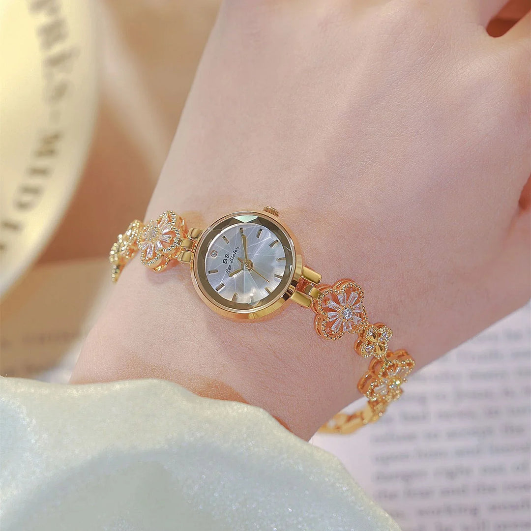 Elegant gold bracelet watch on wrist with floral decorative links and silver dial