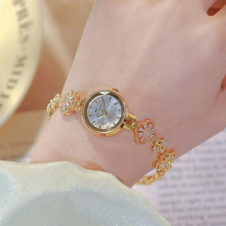 Elegant gold bracelet watch on wrist with floral decorative links and silver dial