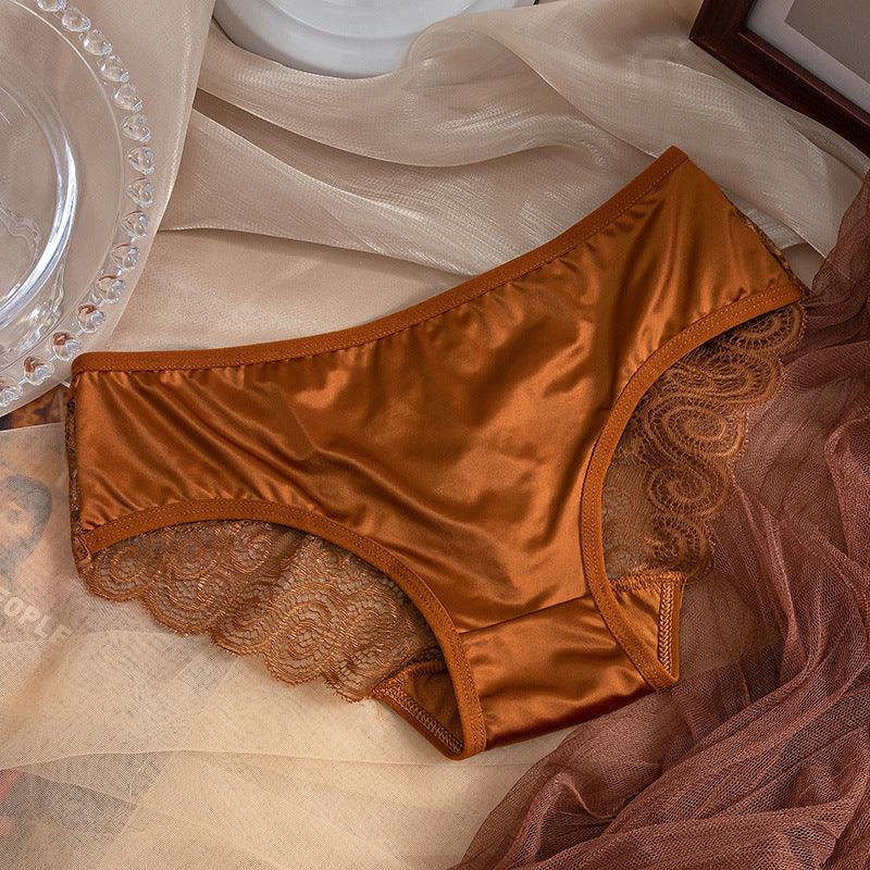 Rust satin women's underwear with lace trim laid on beige and brown sheer fabric