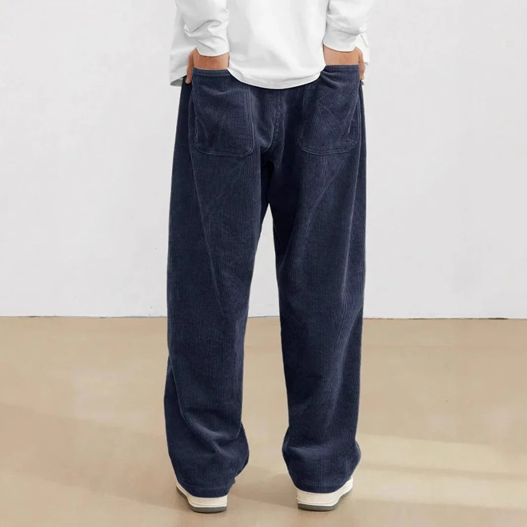 Back view of person wearing loose-fitting navy blue corduroy pants with patch pockets and white sneakers