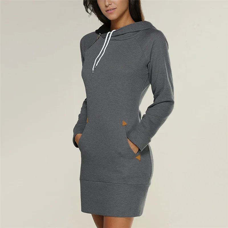 Woman wearing a fitted grey hoodie dress with long sleeves and front pockets with brown accents