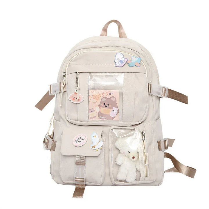 Beige canvas backpack with teddy bear, stickers, and clear front pockets for cute accessories