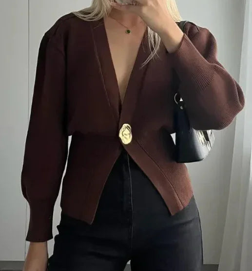 Woman wearing brown V-neck cardigan with gold abstract button and black high-waisted pants, carrying black shoulder bag