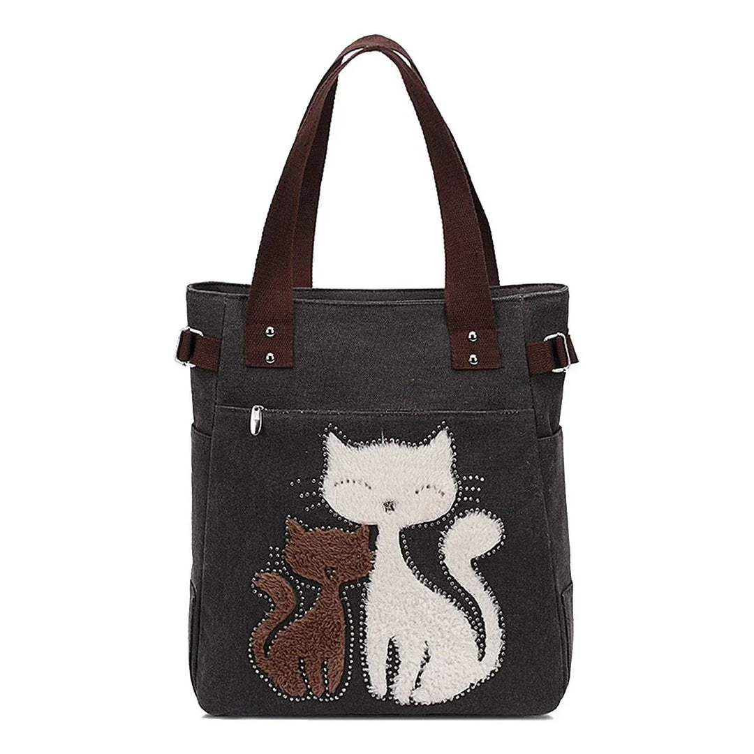 Black tote bag with brown handles featuring cute embroidery of two cats, one white and one brown