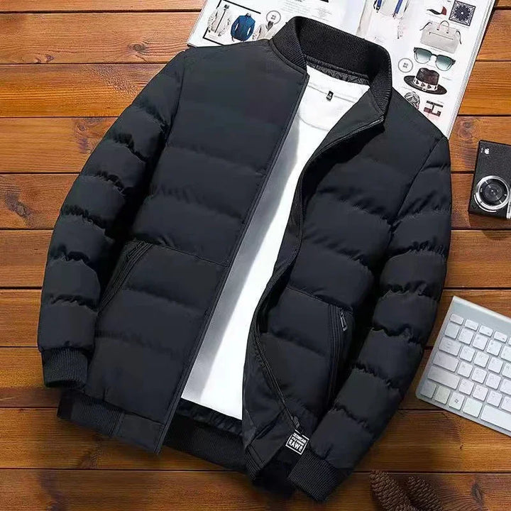 Black puffer jacket with zipper, white inner shirt, on wooden surface with magazine, camera, and keyboard