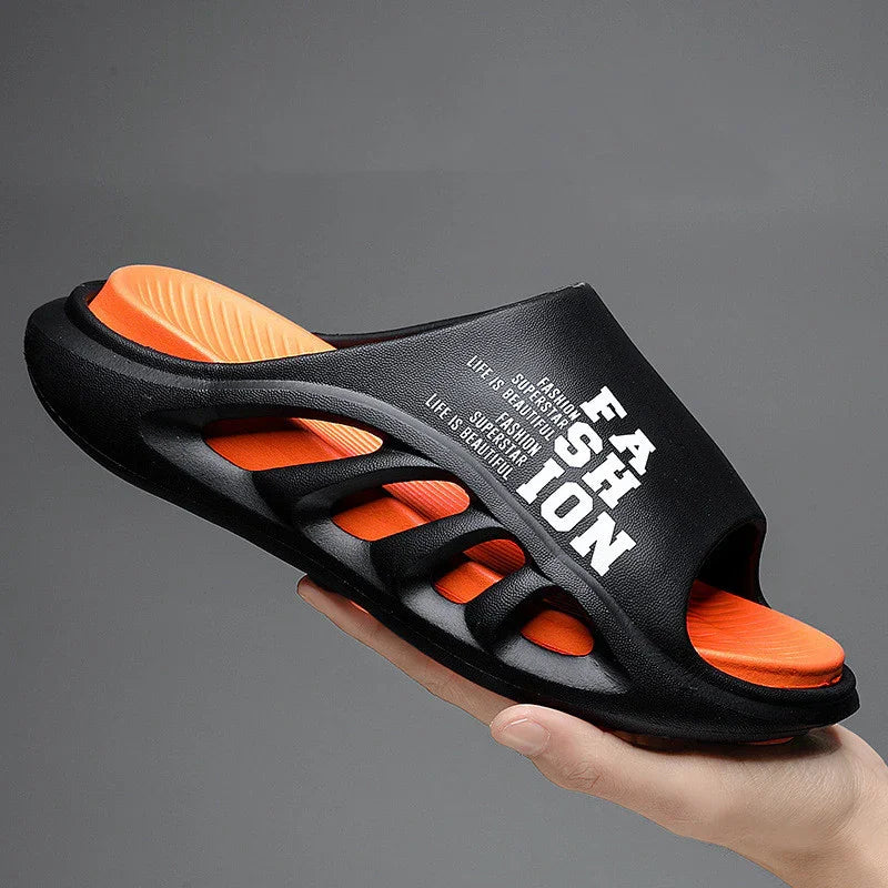 Black and orange fashion slide sandal with cutout design and white printed text held in hand
