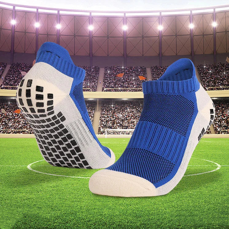 Blue and white low-cut sports socks with anti-slip sole pattern on soccer field background
