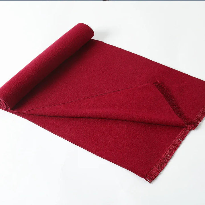 Rolled deep red wool fabric with fringed edges on white background